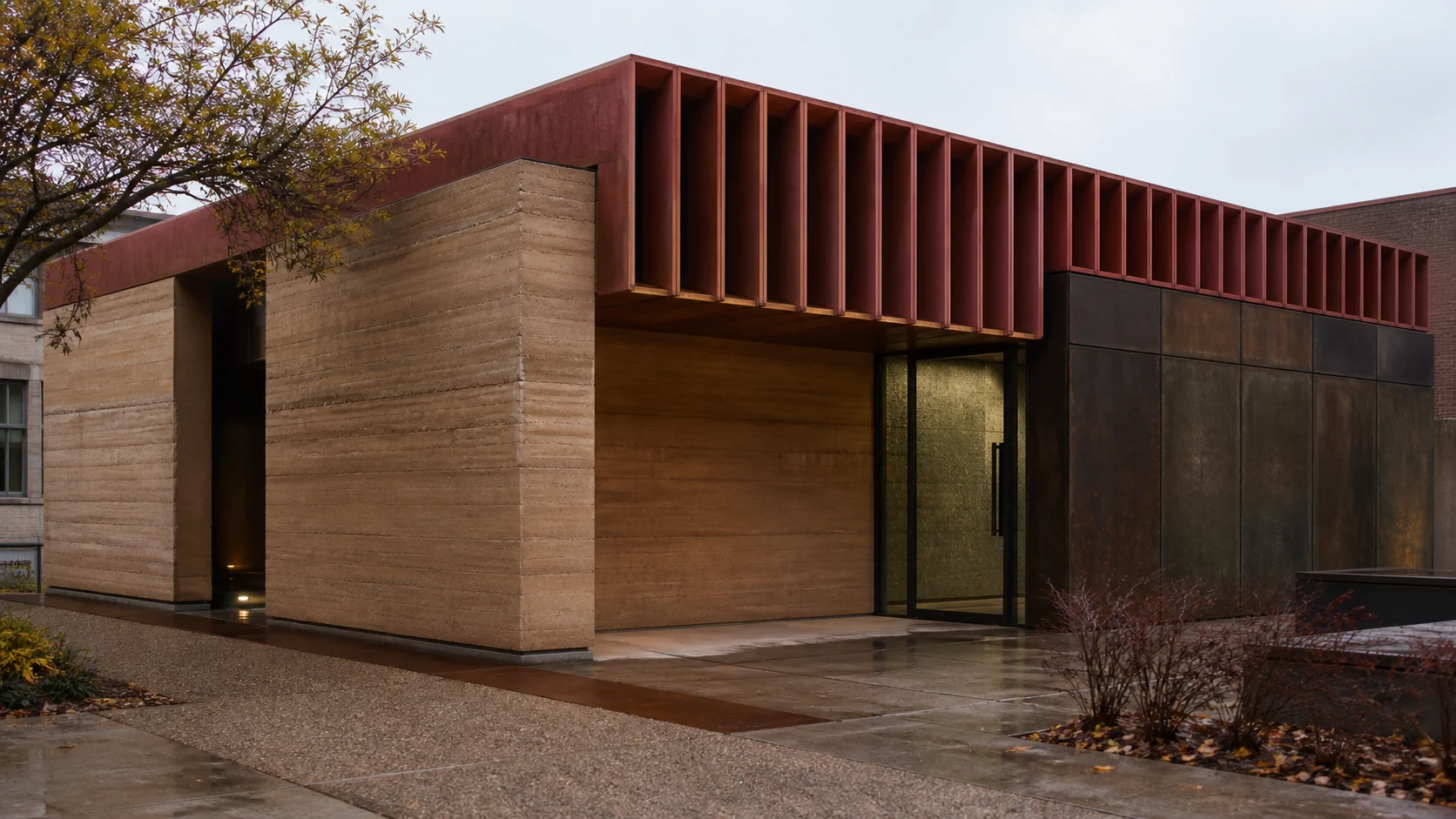 Rammed-earth pavilion with terracotta fins and dark weathered metal panels